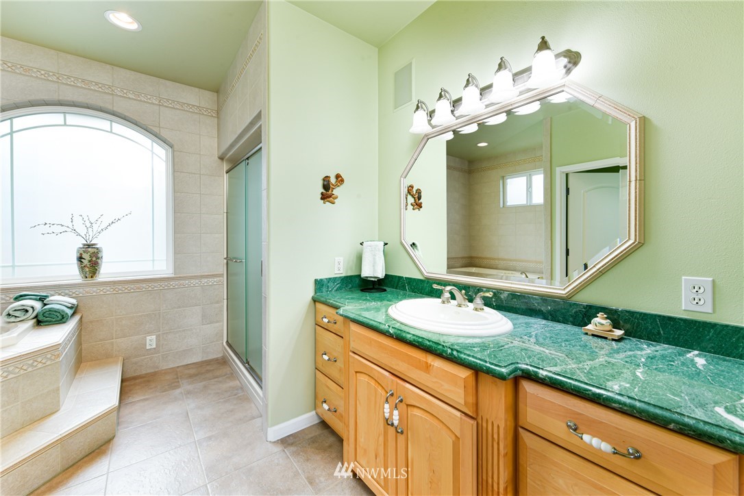 4203 Mitchell Drive Anacortes, WA 98221 - Photo 14 of 38 a bathroom with a granite countertop sink a large mirror and a bathtub