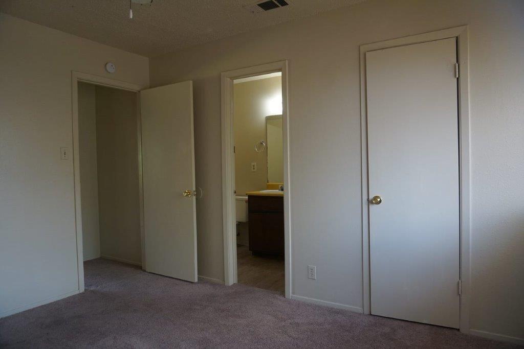 5919 Hidden Valley Trail Austin, TX 78744 - Photo 5 of 8 A well-maintained interior space showcasing comfortable carpeting and convenient access to an adjoining bathroom.