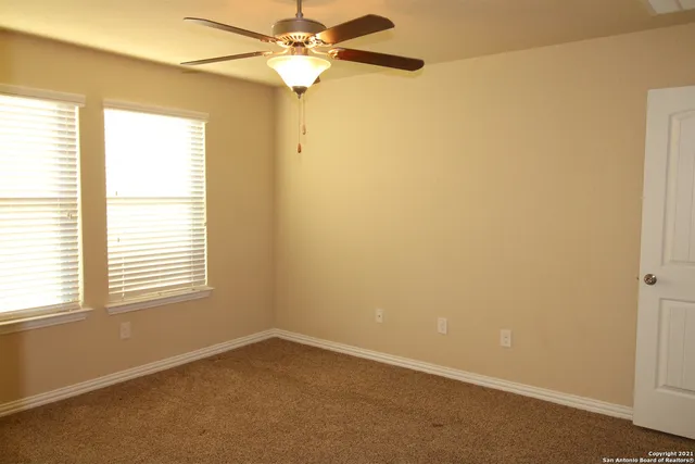 an empty room with a window and a fan