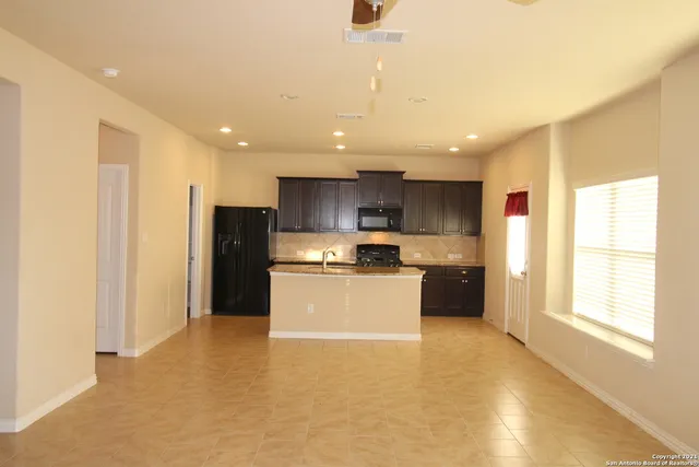 a large kitchen with stainless steel appliances kitchen island a large counter top and a refrigerator