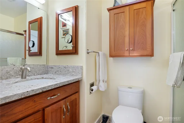 a bathroom with a granite countertop toilet sink and mirror
