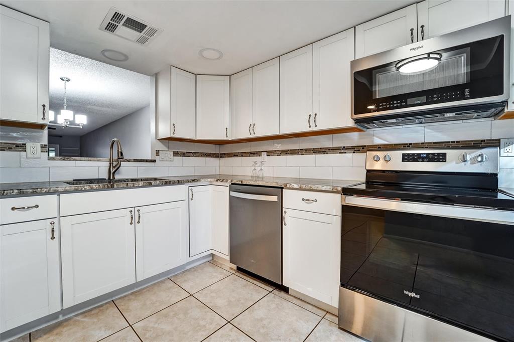 8330 High Point Circle, Unit 6 Port Richey, FL 34668 - Photo 8 of 28 a kitchen with granite countertop white cabinets stainless steel appliances and a sink