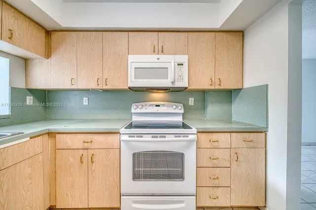a kitchen with granite countertop white cabinets and white appliances