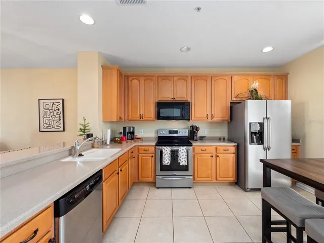 a kitchen with stainless steel appliances granite countertop a sink stove refrigerator and cabinets