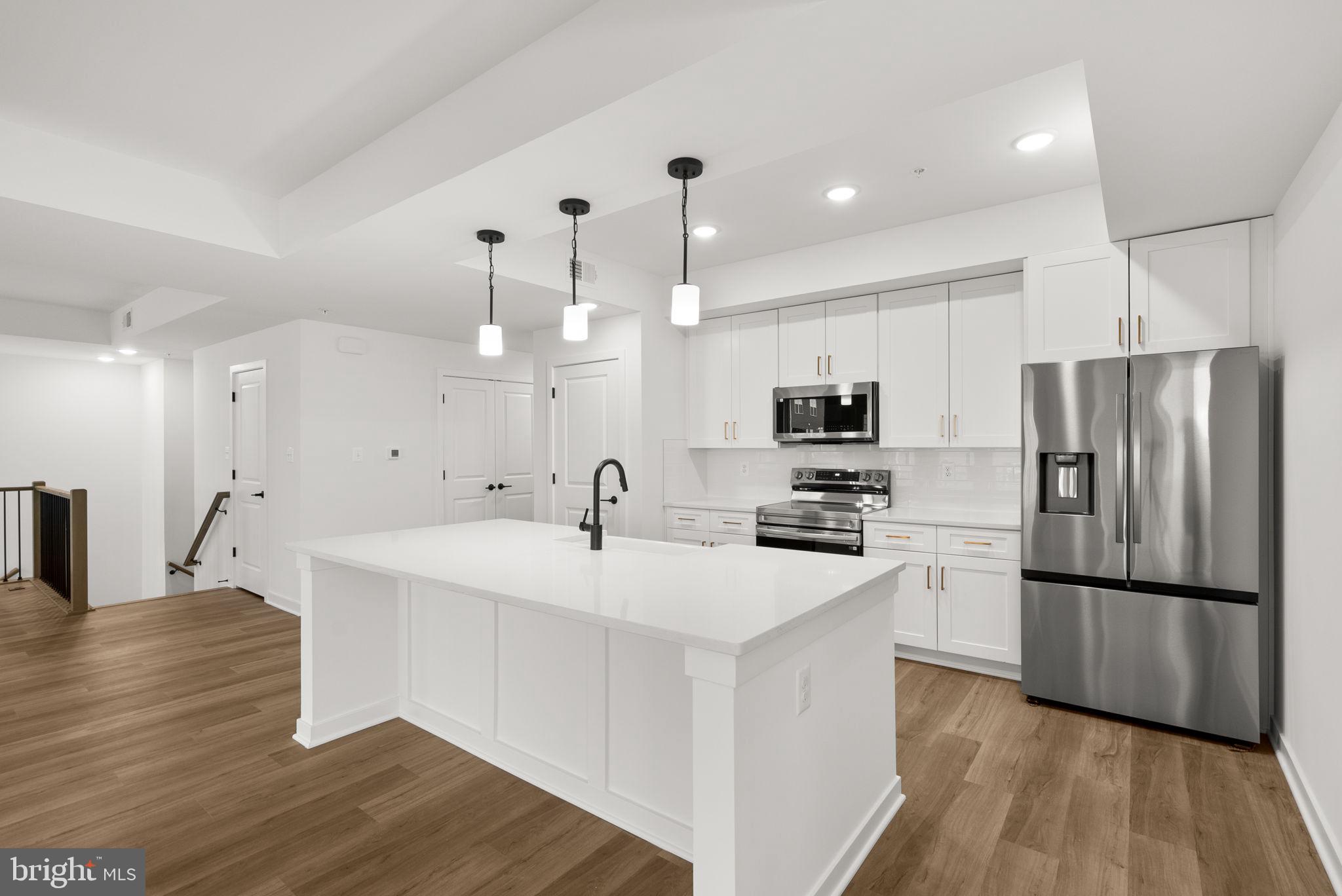 1631 Blacksmith Way, Unit 214B Frederick, MD 21702 - Photo 11 of 41 a kitchen with kitchen island a sink stainless steel appliances and wooden floor