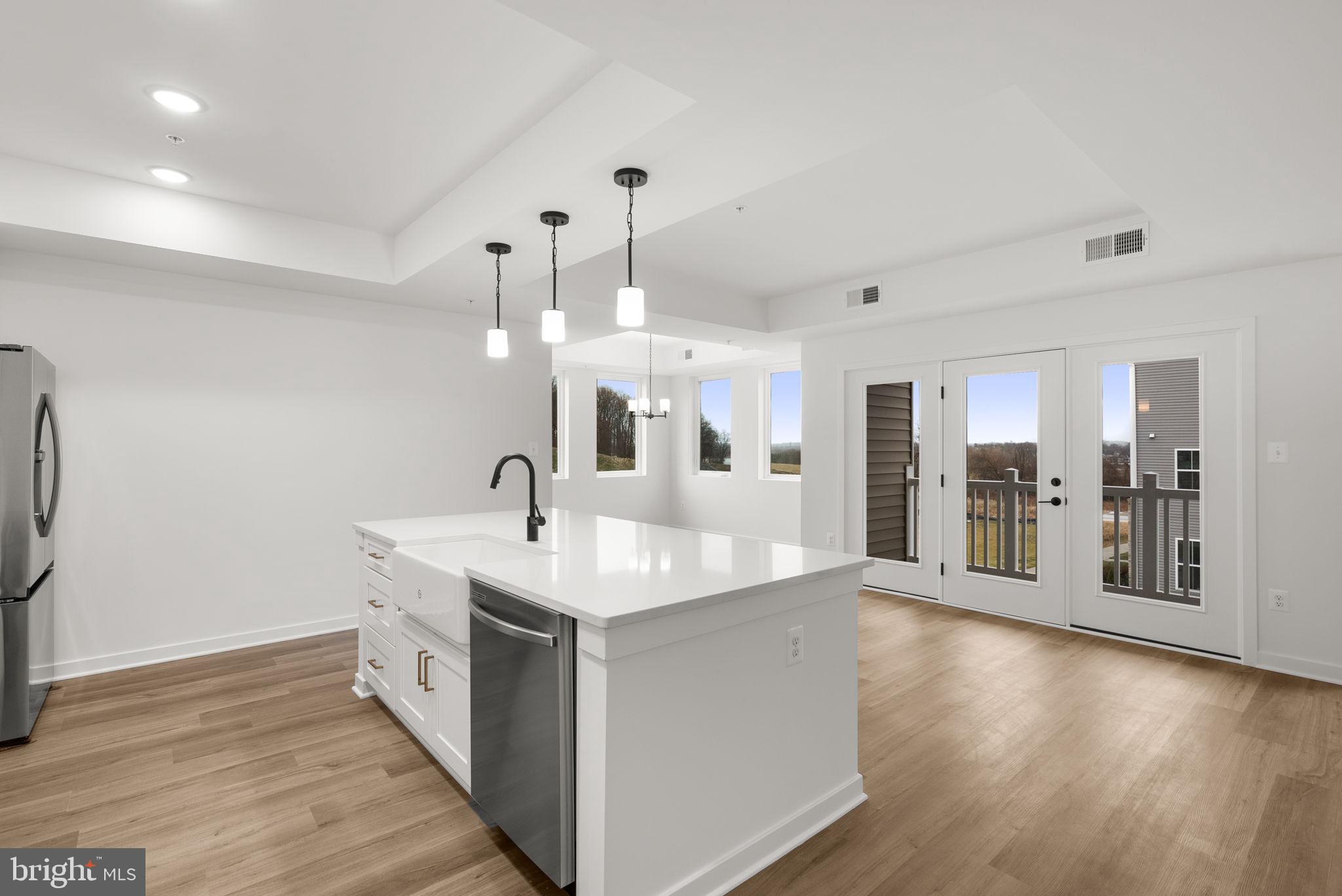 1631 Blacksmith Way, Unit 214B Frederick, MD 21702 - Photo 13 of 41 a large white kitchen with a sink and dishwasher with wooden floor