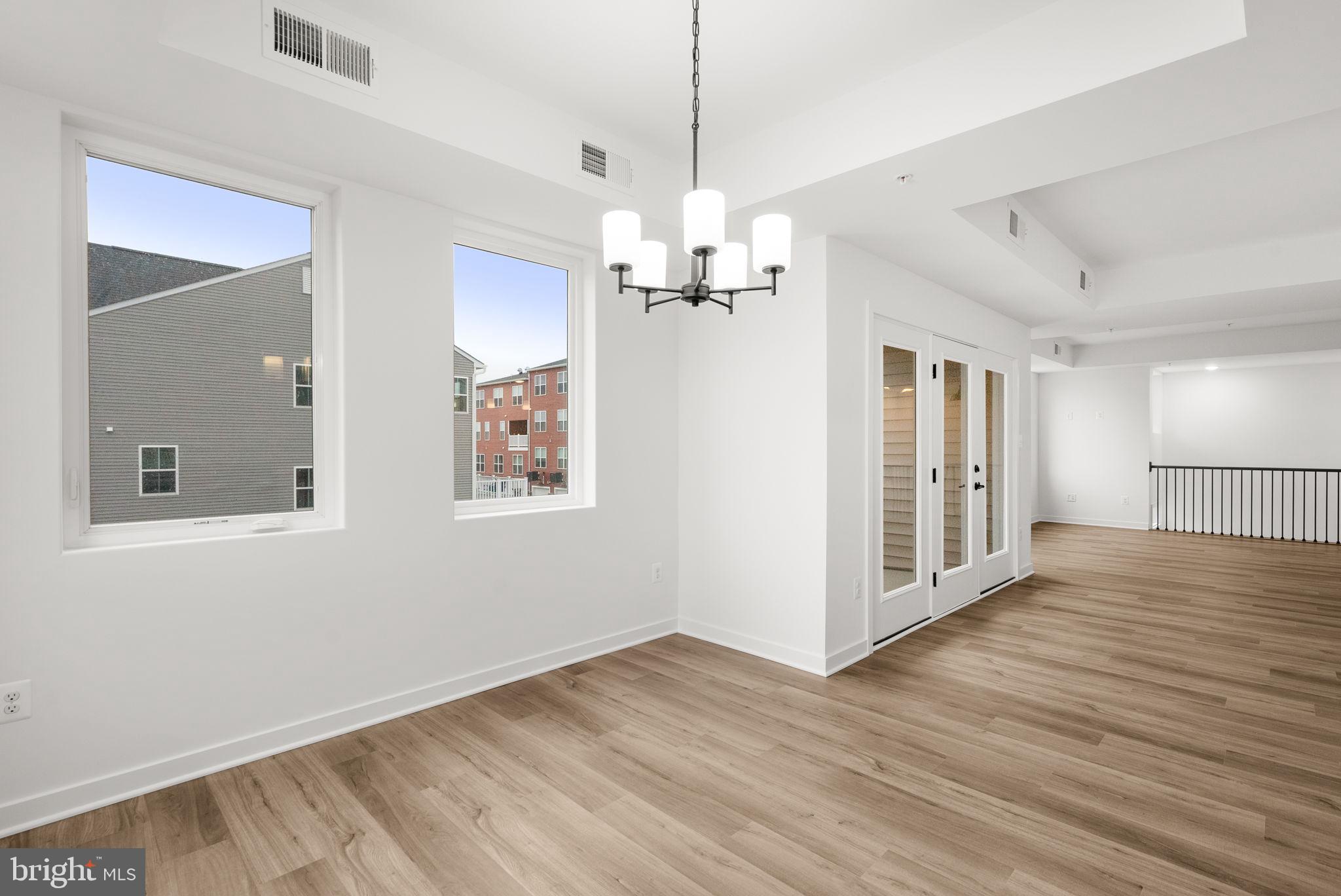 1631 Blacksmith Way, Unit 214B Frederick, MD 21702 - Photo 19 of 41 a view of an empty room with wooden floor and a window