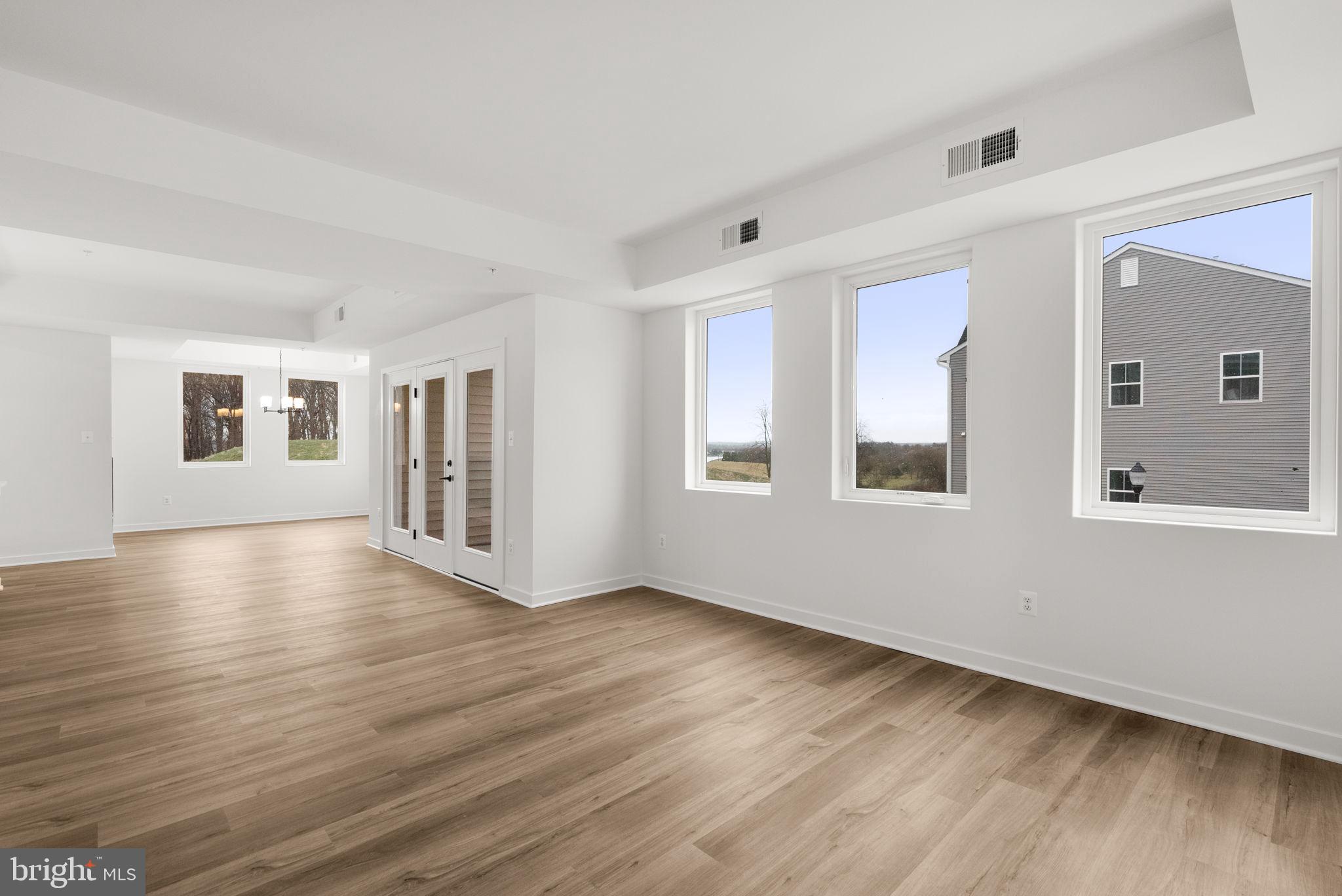 1631 Blacksmith Way, Unit 214B Frederick, MD 21702 - Photo 5 of 41 a view of an empty room with wooden floor and a window