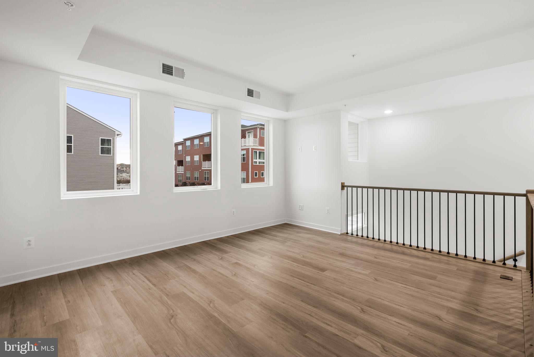 1631 Blacksmith Way, Unit 214B Frederick, MD 21702 - Photo 6 of 41 a view of an empty room with wooden floor and a window