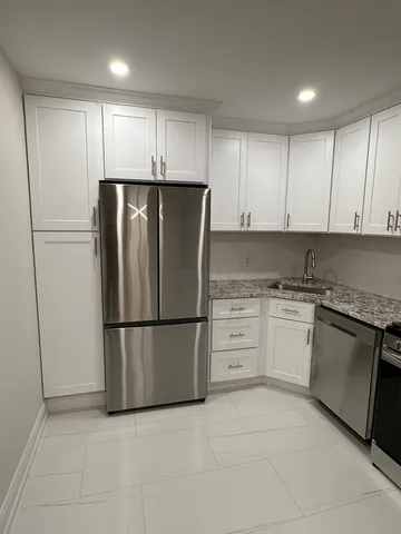 a refrigerator freezer sitting in a kitchen with white cabinets