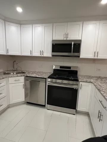 a kitchen with stainless steel appliances granite countertop a stove a sink and a microwave