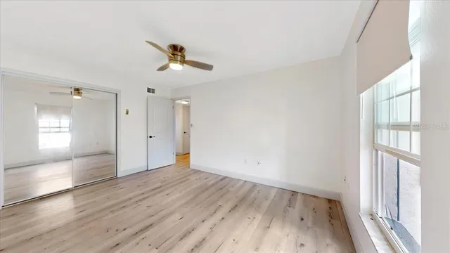 a view of empty room with wooden floor and fan