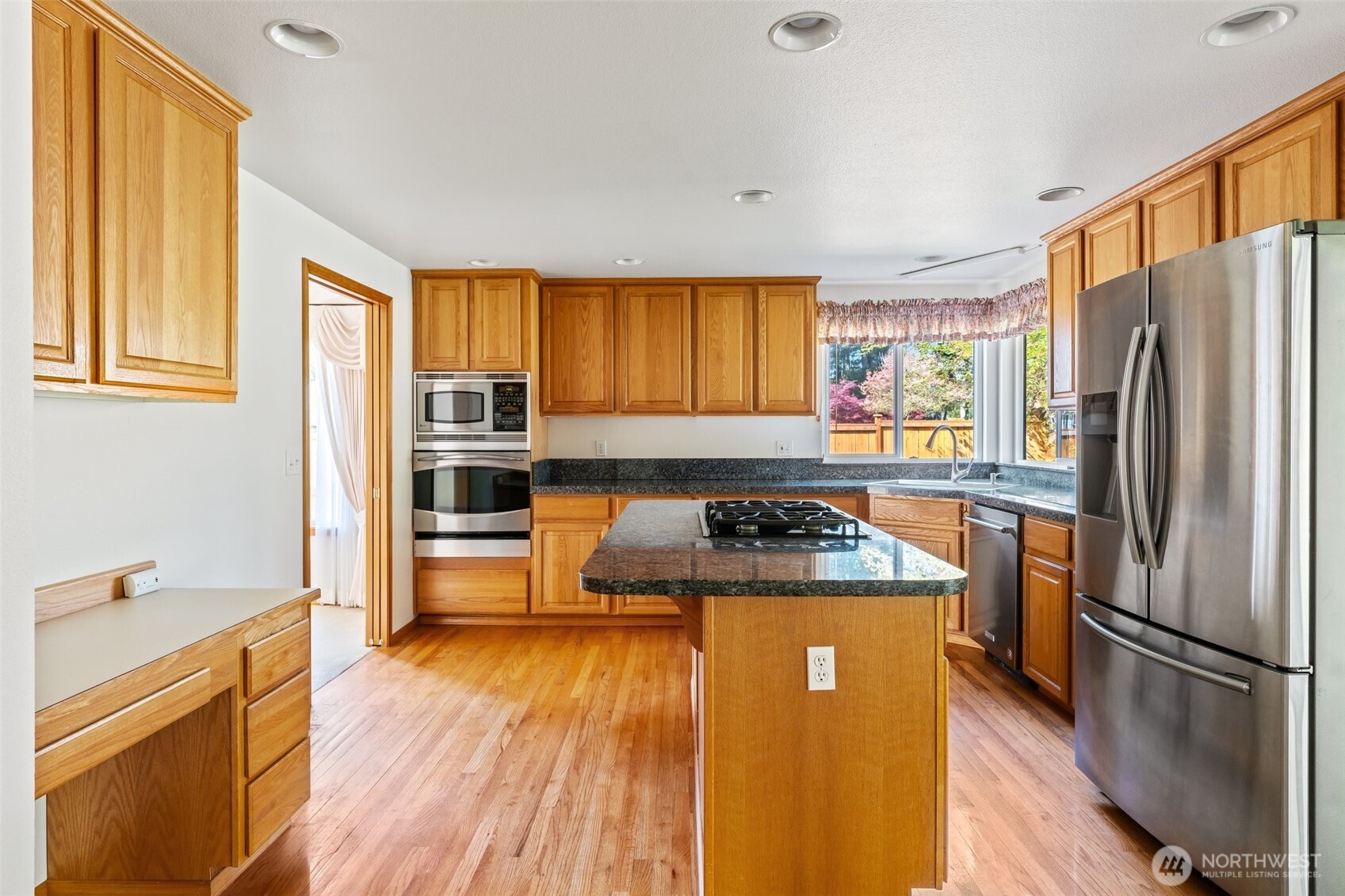 9536 Marlbrook Loop Southeast Olympia, WA 98513 - Photo 20 of 40 a kitchen with stainless steel appliances granite countertop a refrigerator a stove a sink dishwasher and wooden cabinets with wooden floor