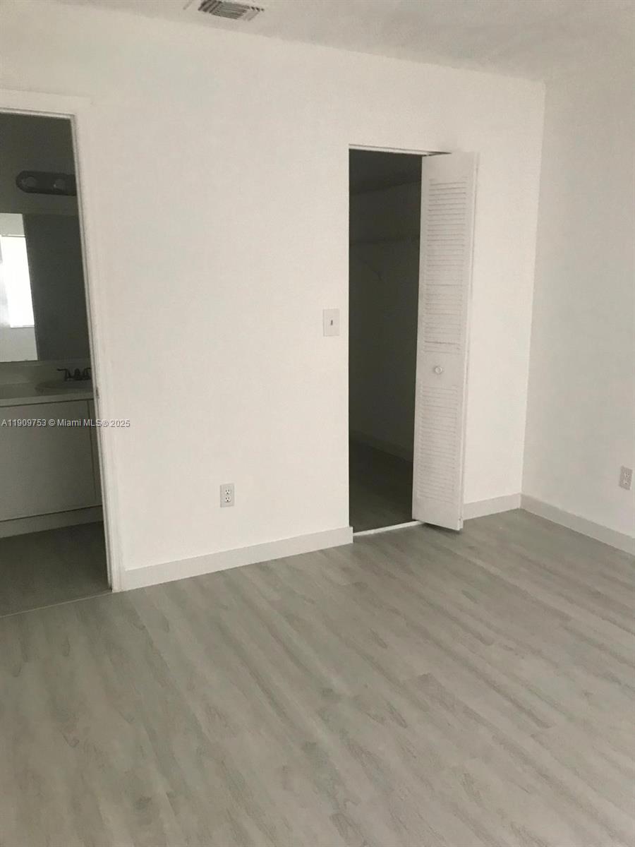 438 Northeast 210th Cir Terrace, Unit 2034B Miami, FL 33179 - Photo 17 of 20 an empty room with wooden floor and windows