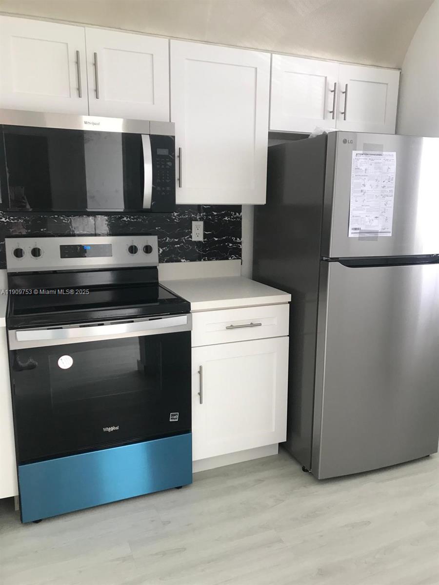438 Northeast 210th Cir Terrace, Unit 2034B Miami, FL 33179 - Photo 5 of 20 a kitchen with stainless steel appliances a refrigerator a stove a microwave and cabinets