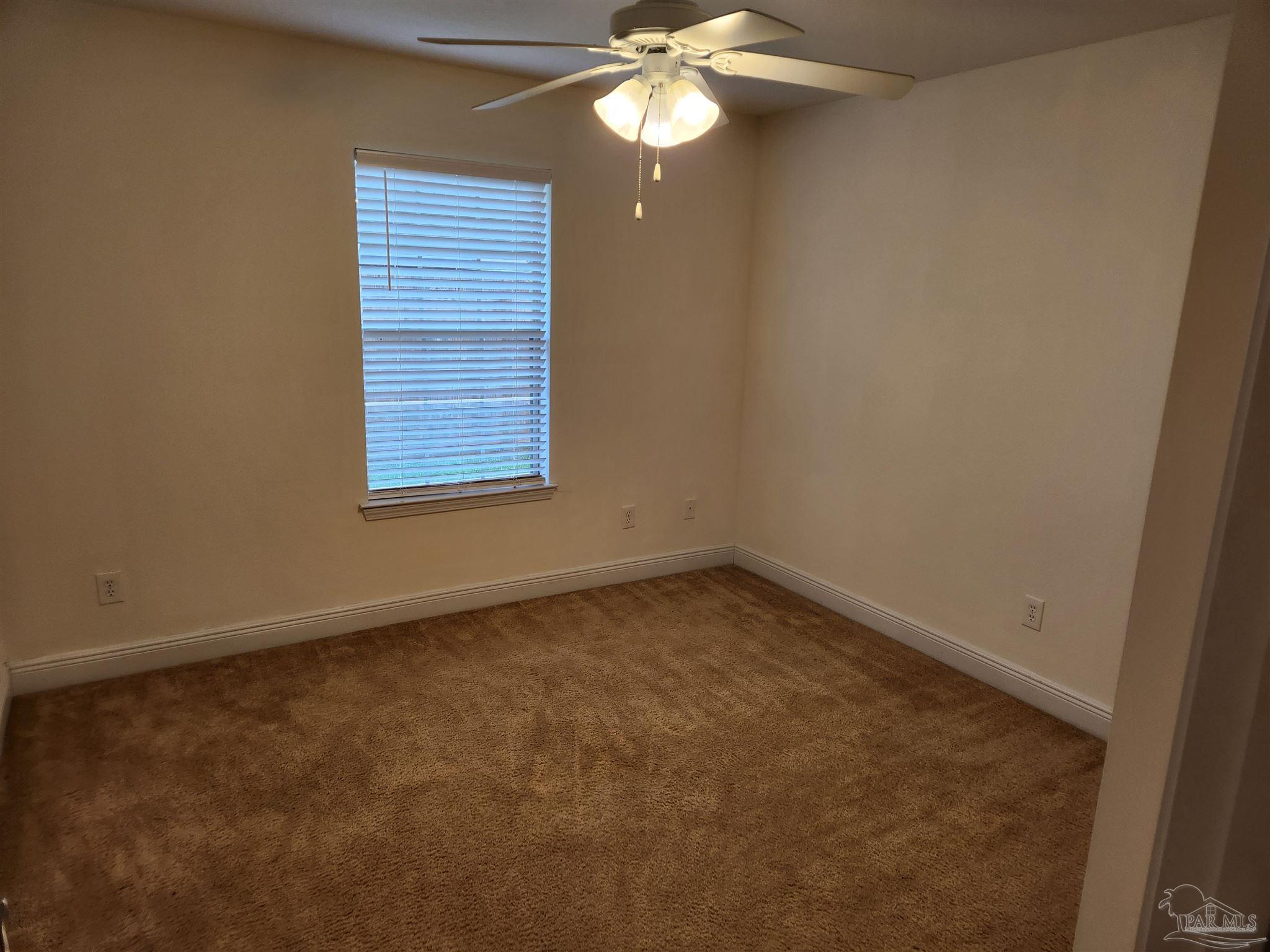 4661 Carmel Circle Pace, FL 32571 - Photo 18 of 26 an empty room with a chandelier fan and window