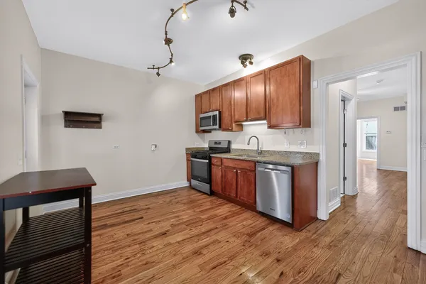 a kitchen with stainless steel appliances granite countertop wooden cabinets a stove a sink and a wooden floors