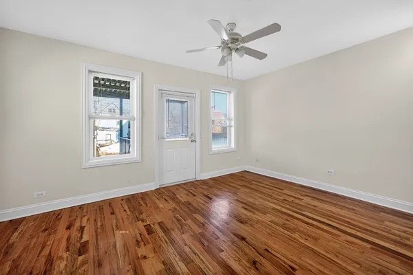 a view of empty room with wooden floor and fan