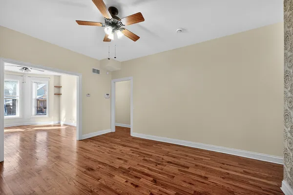 a view of an empty room with window and wooden floor