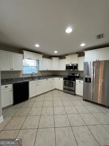 a large kitchen with a stove top oven a sink and cabinets