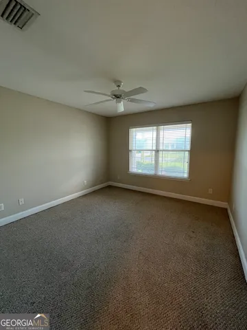 an empty room with a window and a ceiling fan