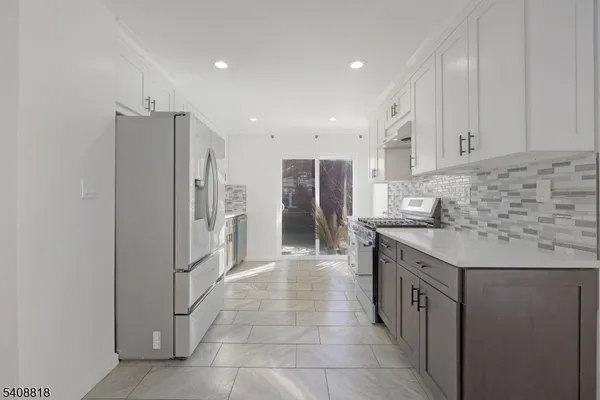 a kitchen with stainless steel appliances granite countertop a refrigerator and a stove top oven