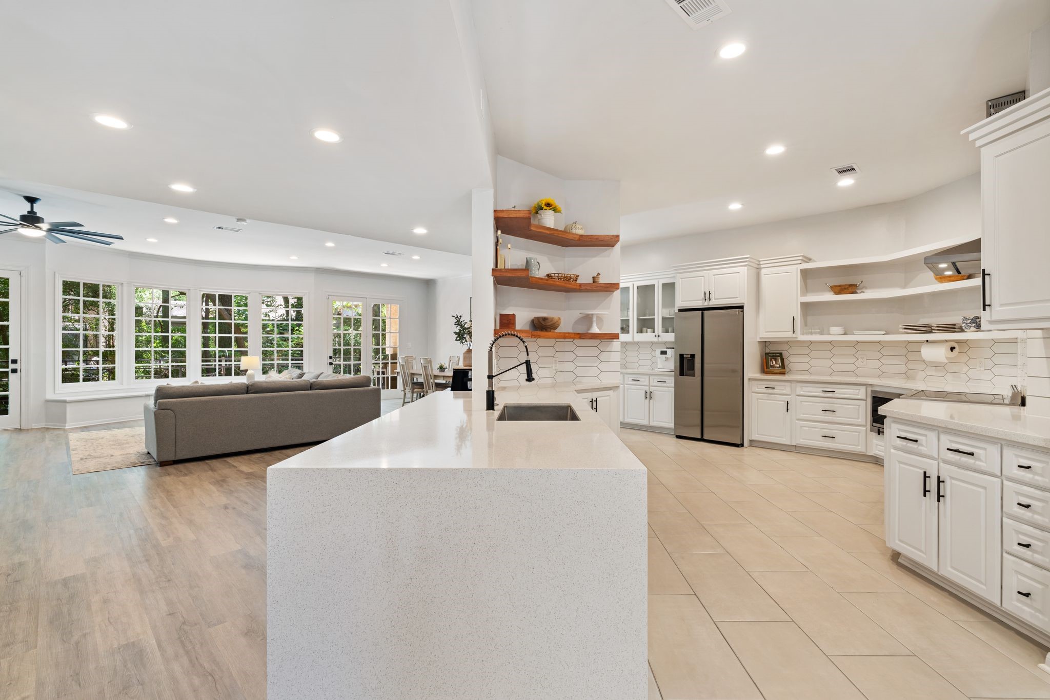 201 Vanderpool Lane, Unit 137 Houston, TX 77024 - Photo 4 of 42 The open concept kitchen flows seamlessly into the family room, anchored by a large waterfall island with quartz countertops. warm wood floating shelves add contrast and character while keeping the space open and connected.