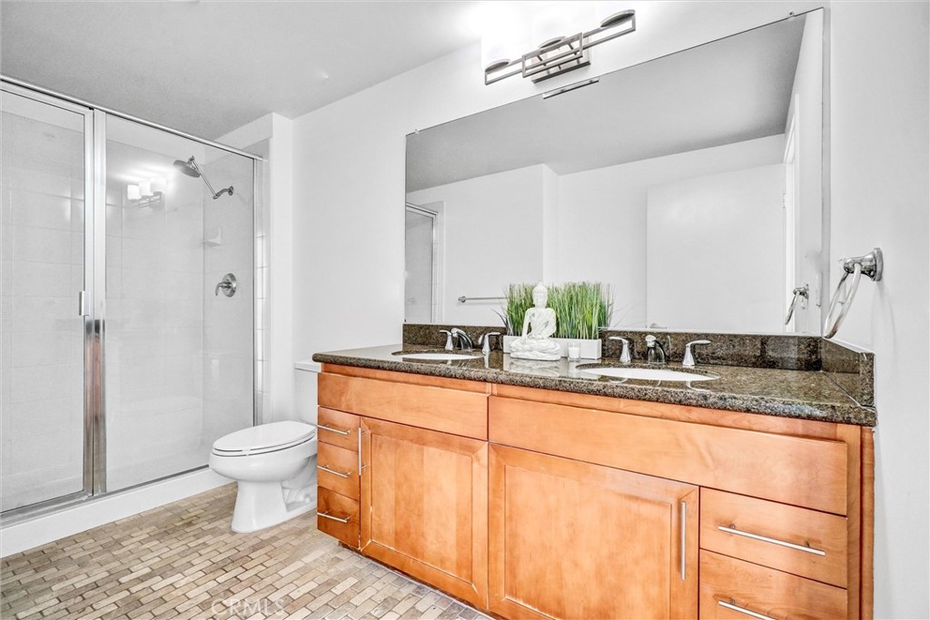 411 West Seaside Way, Unit 1804 Long Beach, CA 90802 - Photo 21 of 55 a bathroom with a granite countertop sink a toilet a mirror and shower