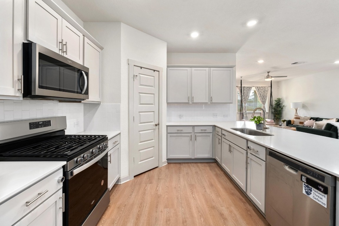 10509 Defender Trail Austin, TX 78754 - Photo 10 of 37 a kitchen with stainless steel appliances a sink dishwasher a stove top oven a refrigerator with white cabinets and wooden floor