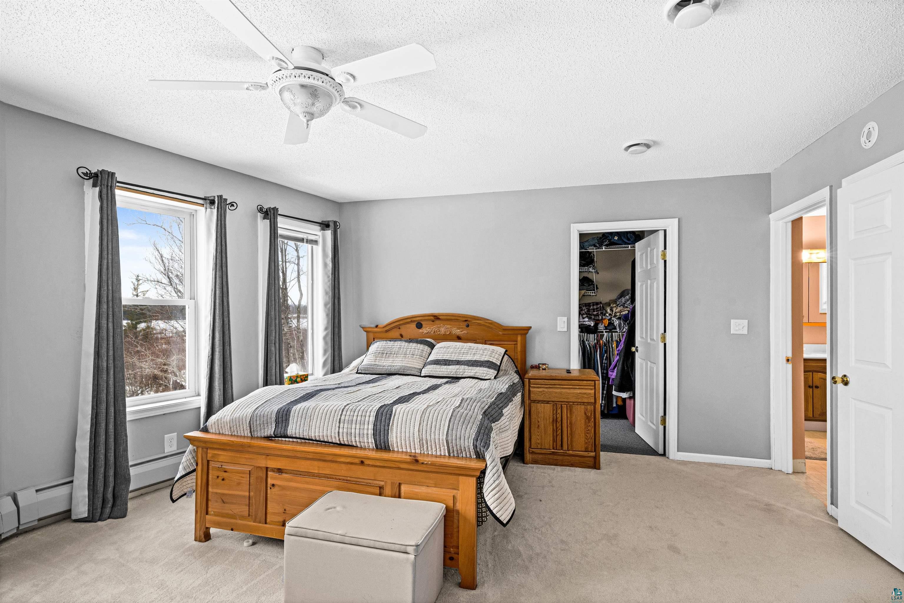 8655 South Lyman Lake Road South Range, WI 54874 - Photo 42 of 64 Bedroom featuring a spacious closet, light carpet, a ceiling fan, and a textured ceiling