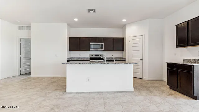 a kitchen with granite countertop a refrigerator and a stove top oven