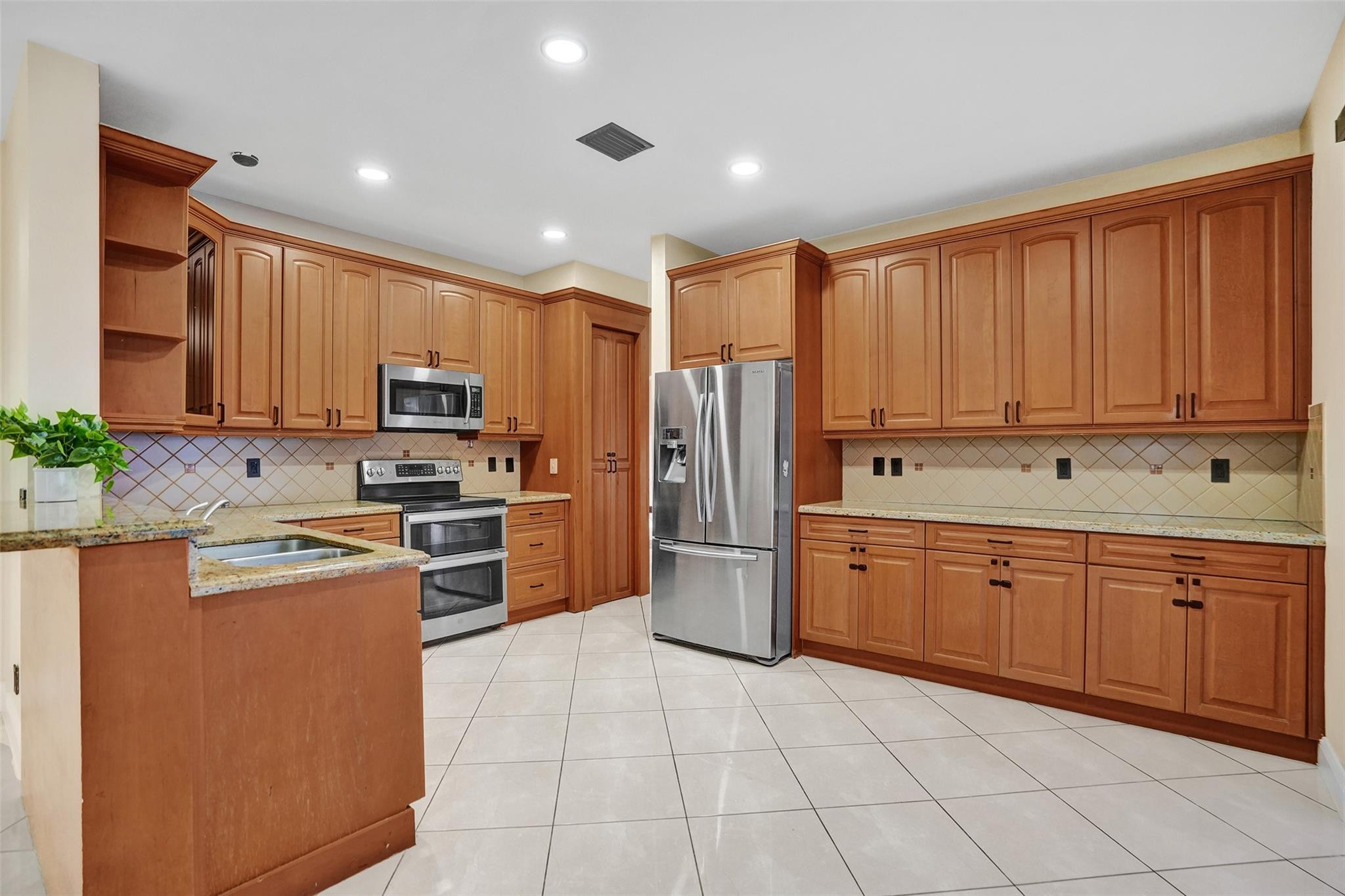 574 Slippery Rock Road Weston, FL 33327 - Photo 21 of 64 a kitchen with stainless steel appliances granite countertop a refrigerator sink and cabinets