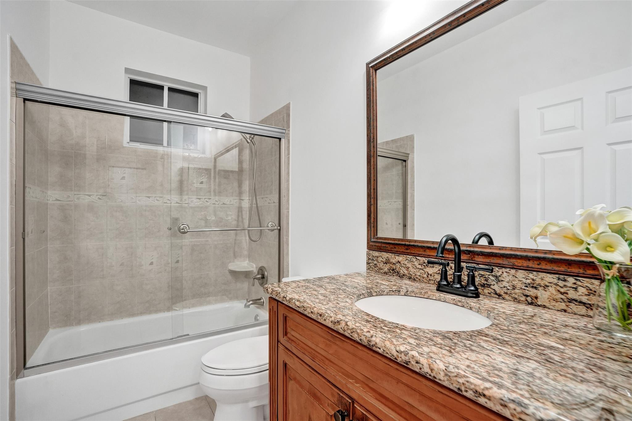 574 Slippery Rock Road Weston, FL 33327 - Photo 31 of 64 a bathroom with a granite countertop sink a toilet a mirror and shower