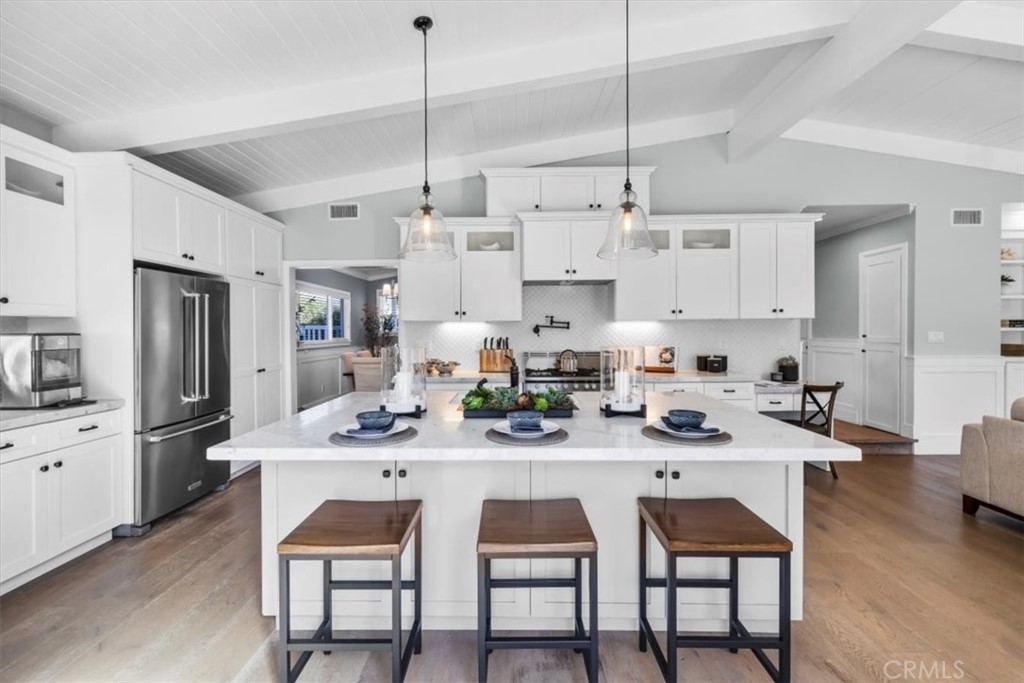 1416 11th Street Manhattan Beach, CA 90266 - Photo 6 of 28 a kitchen with stainless steel appliances kitchen island granite countertop a dining table chairs and white cabinets