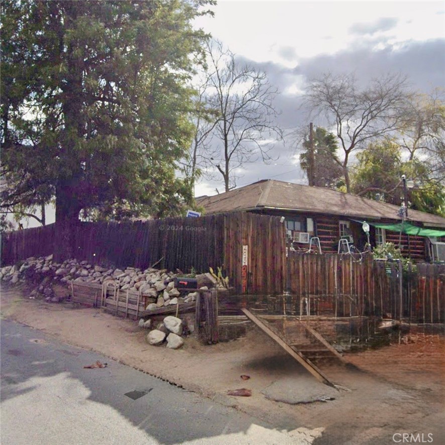a view of backyard with a table and chairs under an umbrella with wooden fence
