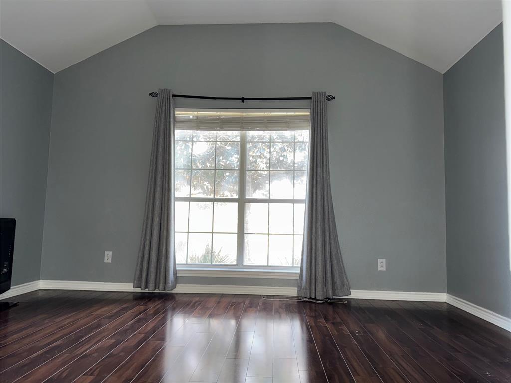 6241 Peach Tree Drive Midlothian, TX 76065 - Photo 7 of 19 Spacious room featuring vaulted ceilings, a large multi-pane window, dark wood-finish flooring, and light gray wall tones with white trim