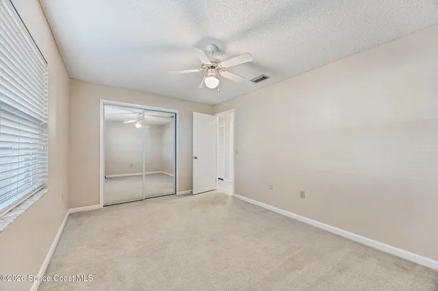 an empty room with a ceiling fan and a window
