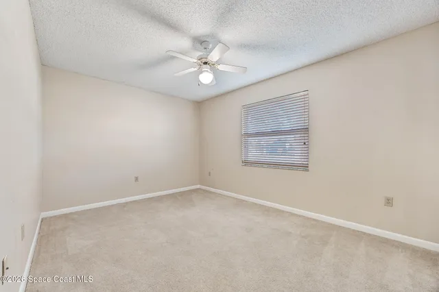 an empty room with a window and a fan