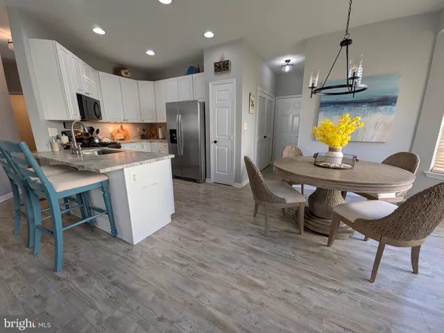 a kitchen with stainless steel appliances kitchen island granite countertop a dining table chairs refrigerator and sink