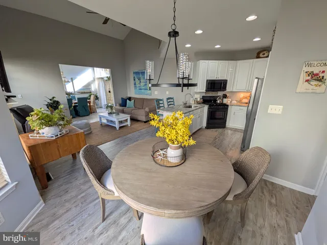 a kitchen with stainless steel appliances kitchen island granite countertop a dining table chairs stove refrigerator and cabinets