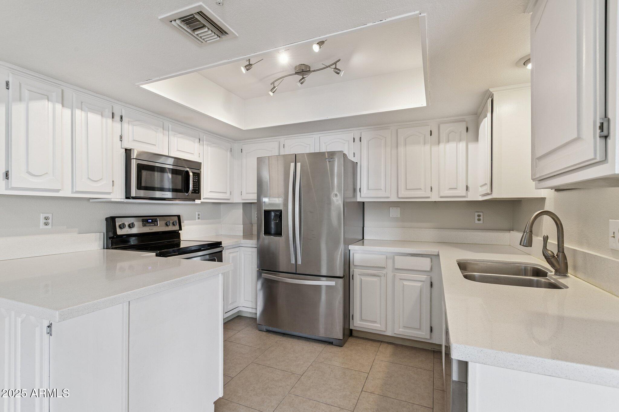 4200 North Miller Road, Unit 220 Scottsdale, AZ 85251 - Photo 6 of 27 a kitchen with stainless steel appliances granite countertop a refrigerator a stove a sink a microwave and wooden cabinets