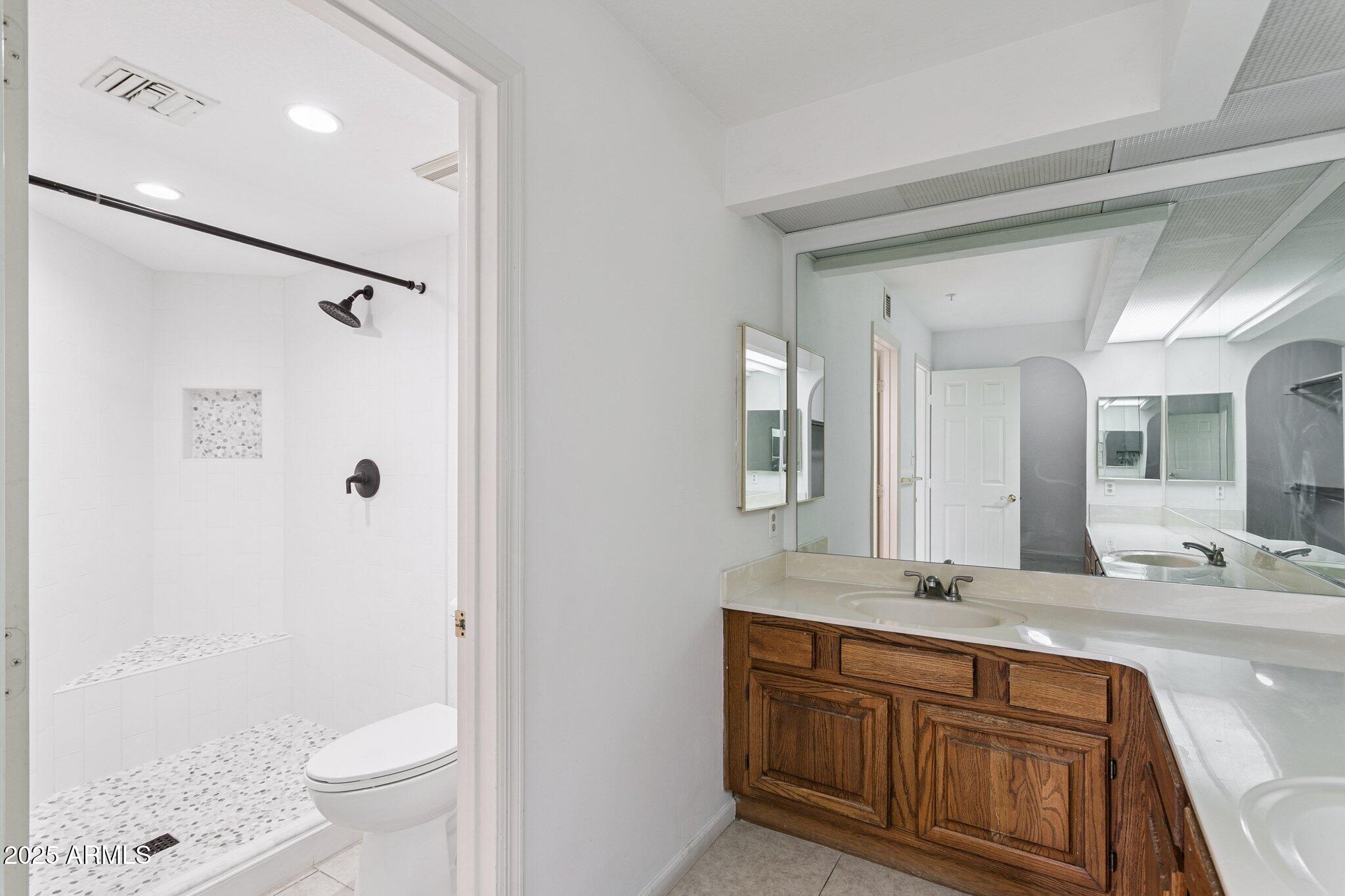 4200 North Miller Road, Unit 220 Scottsdale, AZ 85251 - Photo 8 of 27 a bathroom with a granite countertop sink a mirror a toilet and a shower