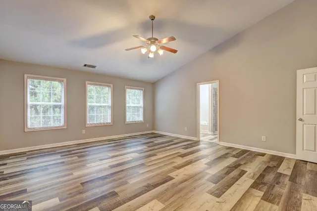 a view of an empty room with window and chandelier fan