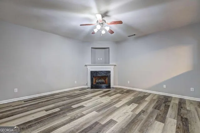 a view of an empty room with a chandelier fan and a fireplace