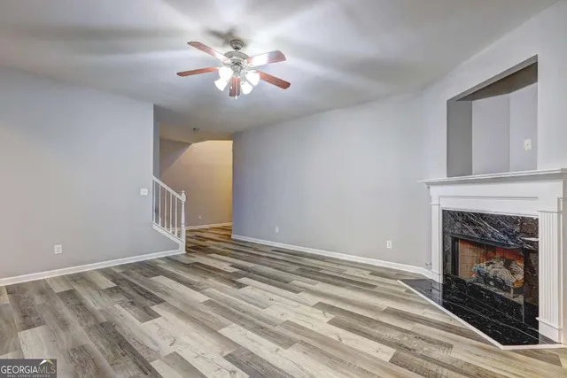 a view of an empty room with chandelier fan and fire place
