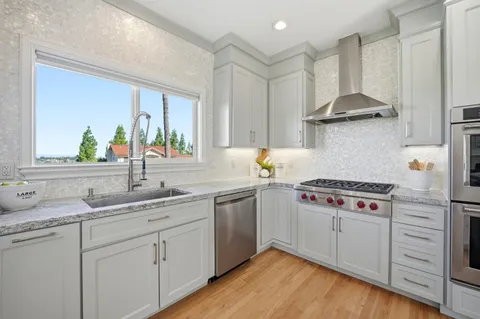 a kitchen with a stove a sink and wooden floor