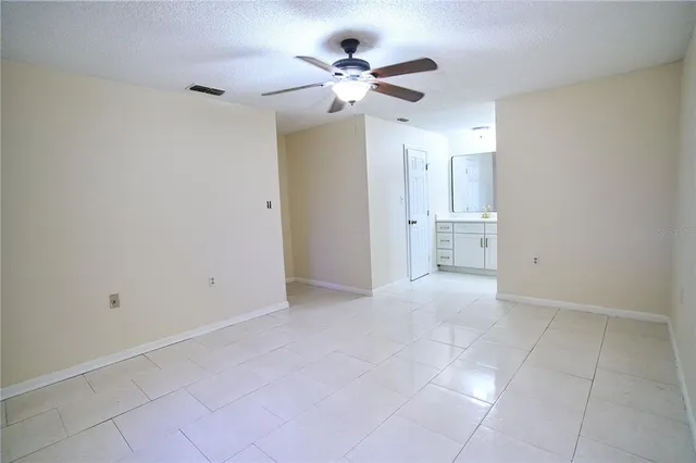 wooden floor in an empty room with a chandelier fan
