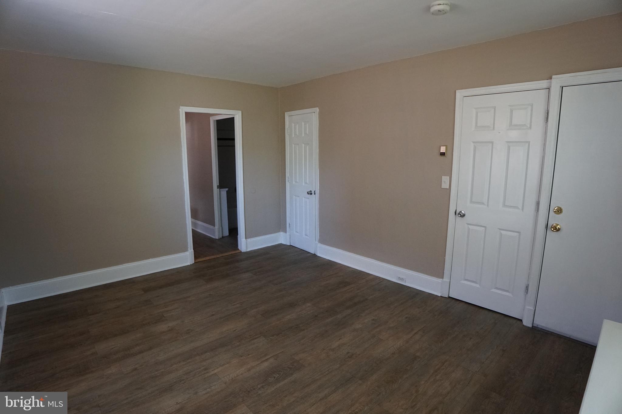 a view of an empty room with wooden floor and closet