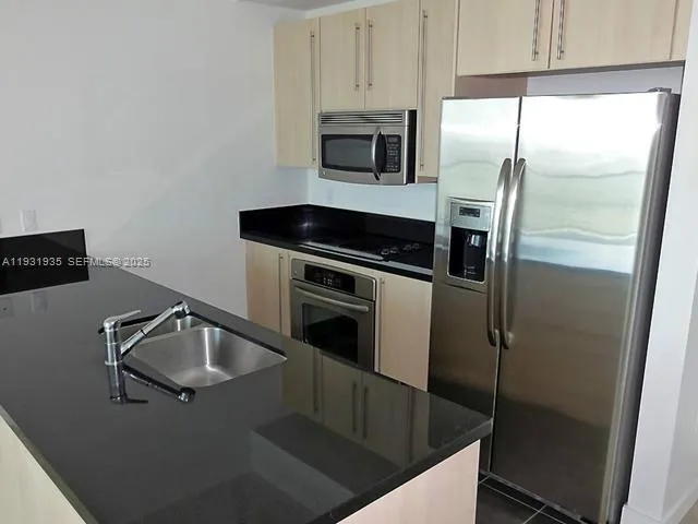 a kitchen with granite countertop a refrigerator sink and stove