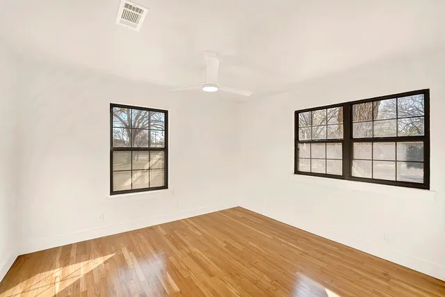 an empty room with wooden floor and windows